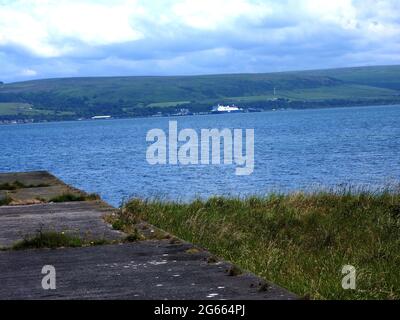 Une vue éloignée du phare de Corsewall (à l'origine Corsill) à Corsewall point sur les Rhins de Galloway, Kirkcolm près de Stranraer, Dumfries et Galloway, en Écosse comme vu de sa route d'approche surplombant la mer d'Irlande. Le phare de Corsewall a été allumé pour la première fois en 1817. Bien qu'il soit encore actif, il est maintenant automatisé, le reste du bâtiment est utilisé comme hôtel. (Photo prise en juin 2021). Il a été construit en 1815 par l'ingénieur Kirkman Finley, qui a été reputé grand-père du constructeur de phare britannique Robert Stevenson qui a notamment conçu et construit le célèbre phare de Bell Rock. Banque D'Images