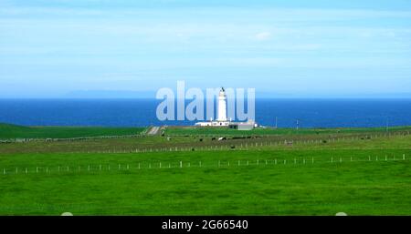 Une vue éloignée du phare de Corsewall (à l'origine Corsill) à Corsewall point sur les Rhins de Galloway, Kirkcolm près de Stranraer, Dumfries et Galloway, en Écosse comme vu de sa route d'approche surplombant la mer d'Irlande. Le phare de Corsewall a été allumé pour la première fois en 1817. Bien qu'il soit encore actif, il est maintenant automatisé, le reste du bâtiment est utilisé comme hôtel. (Photo prise en juin 2021). Il a été construit en 1815 par l'ingénieur Kirkman Finley, qui a été reputé grand-père du constructeur de phare britannique Robert Stevenson qui a notamment conçu et construit le célèbre phare de Bell Rock. Banque D'Images