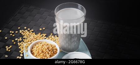 Lait de soja mélangé au sésame noir dans du verre transparent sur un tapis noir. Graines de sésame noir et graines de soja dans une tasse. Lait mélangé de soja de sésame noir. Il Banque D'Images