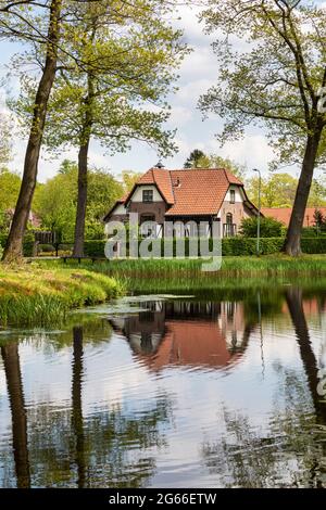 Typique hollandaise authentique maison ancienne près de la rivière avec des reflets dans l'eau, entouré d'arbres et de verdure créant un paysage conscient sur un soleil Banque D'Images