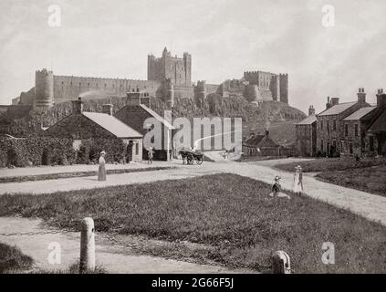 Vue de la fin du XIXe siècle sur le village situé au-dessous du château de Bamburgh, dans le Northumberland, en Angleterre. Les Normands ont construit un nouveau château sur le site, et Henry II a probablement construit le donjon comme il était complet en 1164. En 1464, pendant les guerres des Roses, il devint le premier château d'Angleterre à être vaincu par l'artillerie, à la fin d'un siège de neuf mois par Richard Neville, 16e comte de Warwick, le 'faiseur de roi', au nom des Yorkistes. En 1894, le château a été acheté par l'industriel victorien William Armstrong, qui a terminé la restauration. Banque D'Images