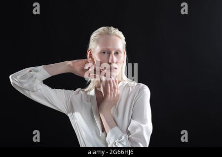 Jeune femme blonde albino faisant la gymnastique faciale automassage et des exercices rajeunissants sur fond noir. Banque D'Images