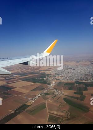 Fenêtres d'avion vue au-dessus de la terre. Vue depuis une fenêtre d'avion sur une aile survolant les terres agricoles et les champs. Banque D'Images