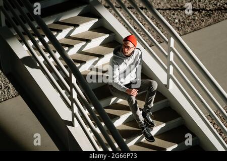 Un boxeur seul sur les escaliers dans le bâtiment urbain de la ville porte des lunettes tendance et des vêtements de mode de rue Banque D'Images