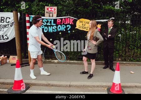 Londres, Royaume-Uni. 2 juillet 2021. Un groupe de militants avec des balles de tennis, des raquettes, des bandeaux et des équipements de tennis géants, et bien placés comme banquiers pour protester devant l'arène de Wimbledon cette année, le tournoi de Wimbledon est parrainé par HSBC, qui est responsable du financement de 81 milliards de livres de combustibles fossiles depuis l'Accord de Paris sur le climat de 2015. Crédit: João Daniel Pereira Banque D'Images