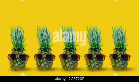 Collection ananas portant des lunettes de soleil rouges sur fond jaune isolé Banque D'Images