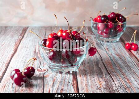 Bol de cerises en verre nivelé sur fond de bois Banque D'Images