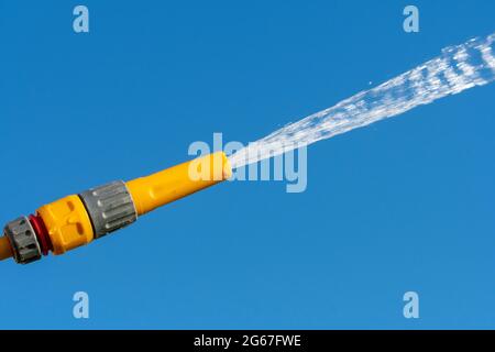 Pulvérisation d'eau à partir d'une pipe à pipe contre un ciel bleu clair, Royaume-Uni. Banque D'Images