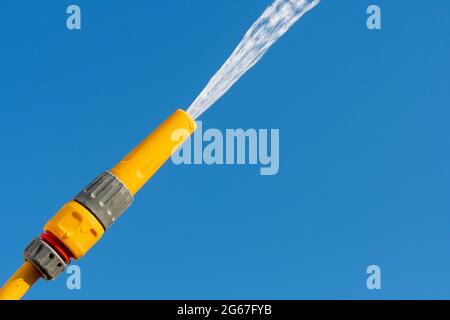 Pulvérisation d'eau à partir d'une pipe à pipe contre un ciel bleu clair, Royaume-Uni. Banque D'Images