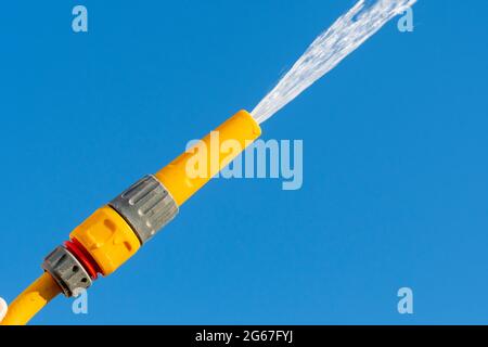 Pulvérisation d'eau à partir d'une pipe à pipe contre un ciel bleu clair, Royaume-Uni. Banque D'Images