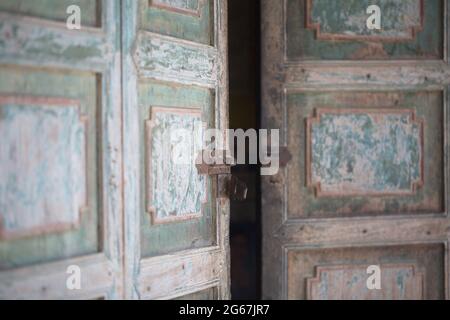 Vieille peinture terne porte en bois à moitié ouverte avec verrouillage en évidence. Phongsali, Laos. Banque D'Images