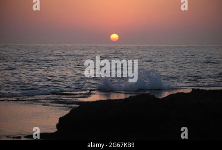 Coucher de soleil, vagues se jetant contre les rochers de grès et les reflets, la mer Méditerranée dans la réserve naturelle de Dor HaBonim Beach. Israël. Banque D'Images