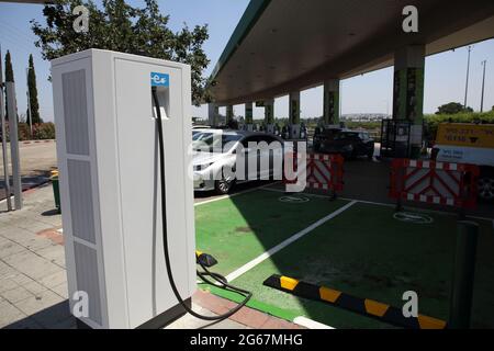 Un poste de charge de voiture électrique avec des places de stationnement vertes pour les voitures électriques seulement dans une station-service ou d'essence régulière. Banque D'Images