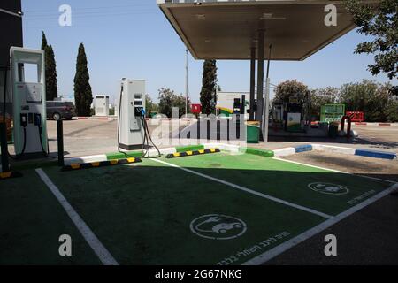 Deux stations de recharge de voitures électriques avec des places de stationnement vertes désignées en hébreu pour les voitures électriques uniquement dans une station-service ou d'essence ordinaire. Banque D'Images
