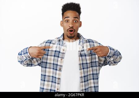 Un homme noir surpris se montrant, un homme afro-américain montrant le logo promo au centre, un gros coup d'œil émerveillé, regarde dans la stupeur, vérifie les remises Banque D'Images