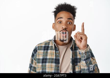 Portrait de l'homme afro-américain excité, étudiant levant le doigt vers le haut dans le geste d'eureka, a suggestion, disant son idée, solution, planifier quelque chose Banque D'Images