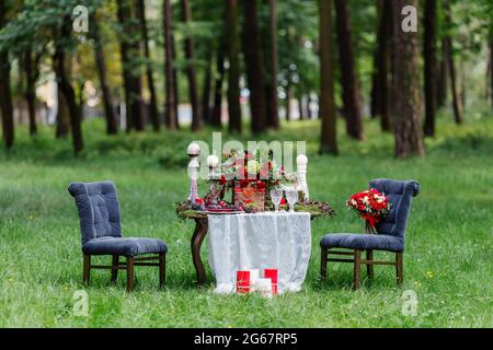 Décoration de table de mariage : chaises et bougies, fleurs, plats en céramique avec fruits, debout sur la nappe en dentelle et la mousse. Détails et décorations de la mariée Banque D'Images