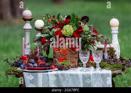 Décoration de table de mariage : chaises et bougies, fleurs, plats en céramique avec fruits, debout sur la nappe en dentelle et la mousse. Détails et décorations de la mariée Banque D'Images