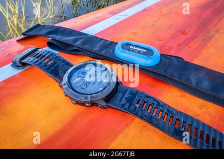 Fort Collins, CO, États-Unis - 23 mai 2021 : Garmin fenix Pro 6X montre solaire sport et moniteur de fréquence cardiaque avec sangle de poitrine sur un pont de paddleboard debout. Banque D'Images