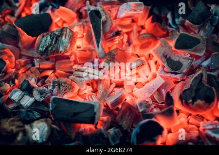 Gravure de charbons. Charbon de bois en décomposition. Les émonteurs de texture se ferment. Le charbon de bois brûlant en arrière-plan. Les charbons brûlants d'un feu.cendres couvantes. Barbecue. Banque D'Images