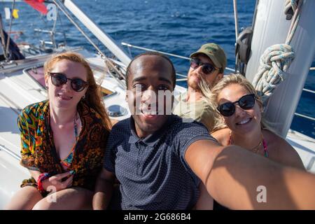 Groupe multiethnique de personnes souriantes dans un bateau prenant un selfie. L'été, l'image, les loisirs et le concept insouciant. Banque D'Images