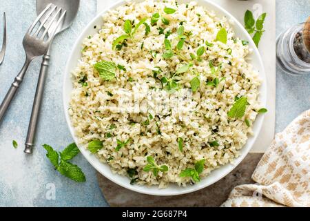 Riz au chou-fleur avec herbes et jus de citron dans un bol blanc Banque D'Images