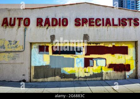 Un bâtiment industriel abandonné avec une porte de garage en métal ondulé graffière peinte avec des blocs multicolores de peinture de couverture graffiti Banque D'Images