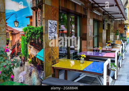 Des tables multicolores à la mode avec des fleurs et des bancs à l'extérieur d'un restaurant à la mode avec une affiche du lac de Côme, dans Little Italy, San Diego, CA Banque D'Images