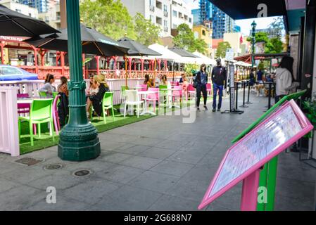 Menus au premier plan de la scène de la rue, avec des personnes se balader près des restaurants sur India Street, avec des structures de restauration extérieures et des parasols à Littl Banque D'Images