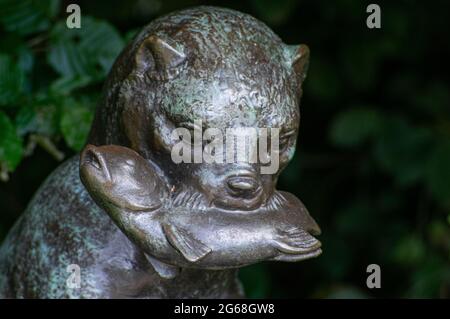 statue en bronze d'une loutre (lutra lutra) se nourrissant d'un poisson. gros plan de la tête de loutre Banque D'Images