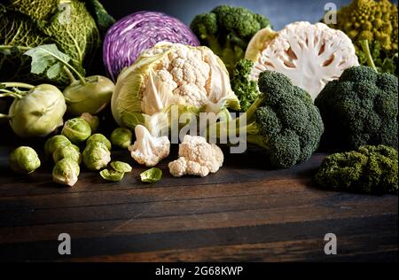 Divers types de cabages frais mûrs disposés sur une table en bois sombre dans le studio Banque D'Images