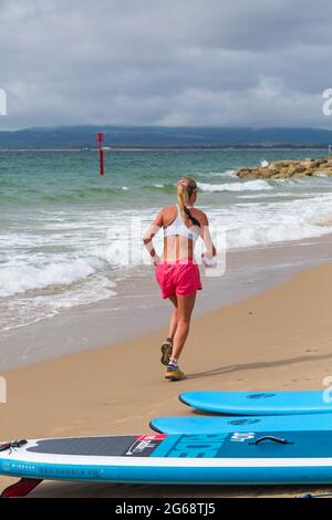 Poole, Dorset Royaume-Uni. 4 juillet 2021. Météo au Royaume-Uni : nuageux et venteux avec des intervalles ensoleillés sur les plages de Poole. Coureur courant le long de la mer à Branksome Chine. Crédit : Carolyn Jenkins/Alay Live News Banque D'Images