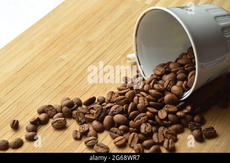 Grains de café frais soigneusement sélectionnés et torréfiés à l'intérieur de la tasse, sur une table en bois Banque D'Images