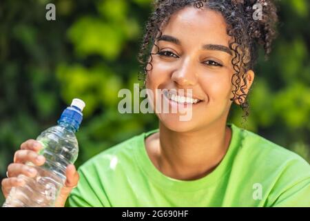 Portrait en plein air de la belle course mixte africaine fille américaine adolescente jeune femme avec des dents parfaites boire de l'eau d'une bouteille lasse Banque D'Images