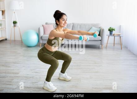 Concept d'entraînement de force. Faites des squats avec des haltères chez une femme indienne Banque D'Images
