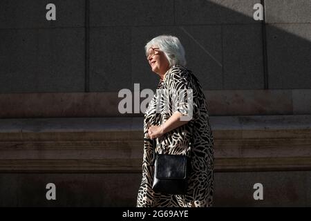 femme âgée marchant au coucher du soleil dans la ville Banque D'Images