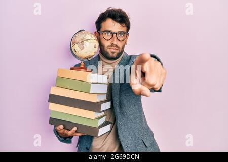 Beau homme avec un professeur de géographie de la barbe pointant du doigt vers l'appareil photo et vers vous, geste confiant et sérieux Banque D'Images