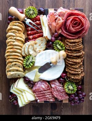 Vue de haut en bas d'un plateau de charcuterie à base de viande et de fromage sur un fond en bois. Banque D'Images