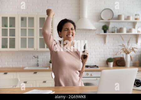 Femme sincère du millénaire joyeuse célébrant la victoire en ligne. Banque D'Images