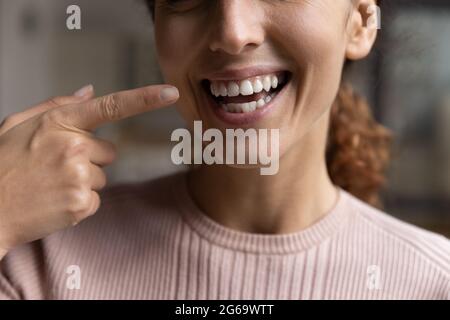 Une jeune femme heureuse pointe le doigt vers un sourire blanc crasseux. Banque D'Images