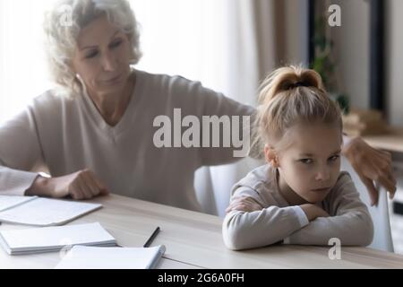 Vieille dame enseignant regarder la fille désobéissante refusant d'étudier Banque D'Images