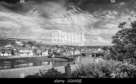 Port et ville de Whitby avec vue vers l'intérieur. Les bâtiments de la ville se regroupent autour du port et un pont traverse l’eau. Une arborescence se trouve au premier plan. Banque D'Images