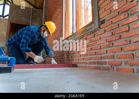 artisan tiler les mains travaillant sur une nouvelle entrée de maison, un homme de main local et professionnel appliquant des tuiles sur le chantier de construction Banque D'Images