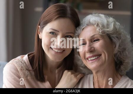 Une fille adulte souriante embrasse les épaules de la mère plus âgée partagent une humeur optimiste Banque D'Images