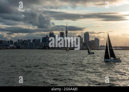 Célèbre horizon du quartier central des affaires d'Auckland au coucher du soleil, les gens se réjouissant de la chaude soirée d'été sur leurs voiliers, Nouvelle-Zélande Banque D'Images