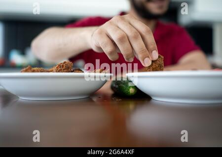 Un garçon arabe qui mange à la maison a fait du falafel à l'intérieur Banque D'Images