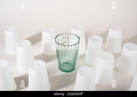 Verre parmi de nombreuses tasses en plastique. Verre ou plastique. Réutilisables ou jetables. Concept zéro déchet. Arrêtez la pollution plastique. Banque D'Images