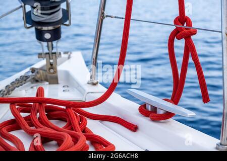 Bateau à voile amarrer des cordes sur le pont. Corde de yachting de couleur rouge attachée sur la cale, modèle de carte de croisière. Outils et équipements de sécurité Voilier, vue rapprochée Banque D'Images