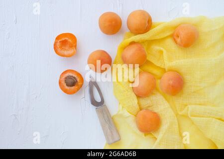 Délicieux abricots avec petit couteau sur la table gros plan. Vue horizontale depuis le dessus avec serviette jaune. Banque D'Images