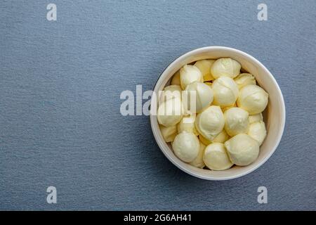 Fromage mozzarella. Boules blanches de fromage mazzarella dans une assiette sur fond de pierre noire avec place pour insérer le texte Banque D'Images